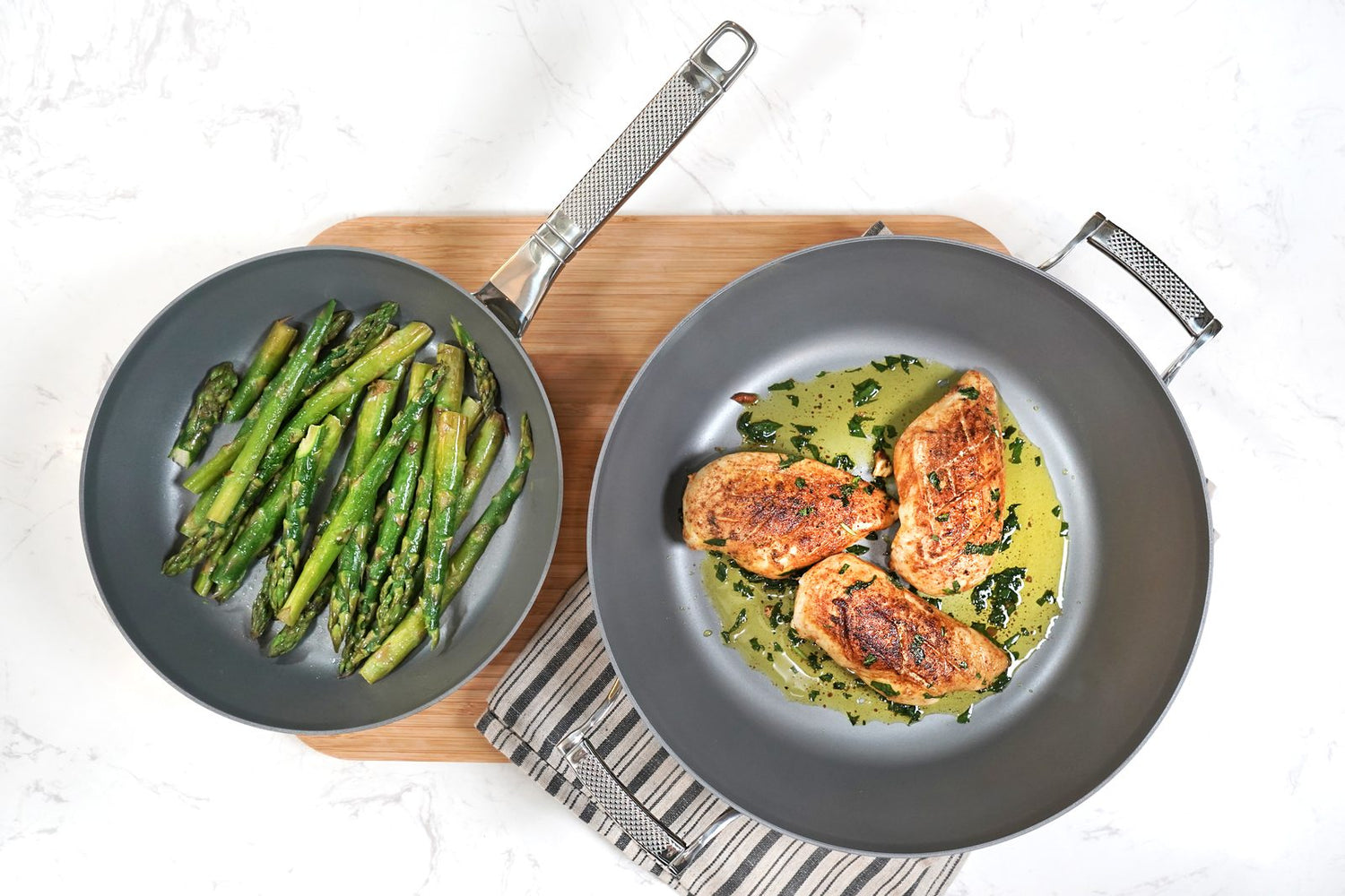 Two Saveur Selects non-stick frying pans with cooked vegetables and salmon, shown from above