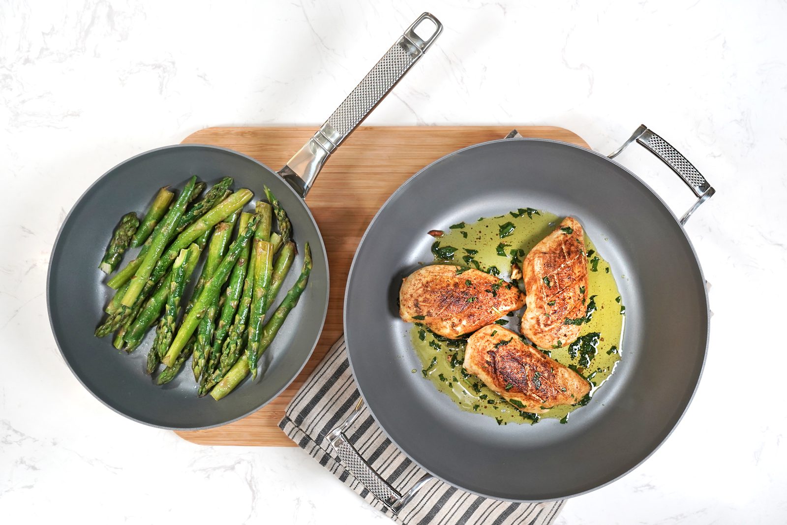 Two Saveur Selects non-stick frying pans with cooked vegetables and salmon, shown from above